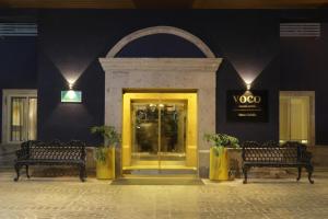 萨尔蒂约voco Saltillo Suites, an IHG Hotel的商店前有两把长凳和一扇黄色的门