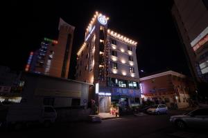 昌原市格雷酒店的一座高大的建筑,晚上有 ⁇ 虹灯标志