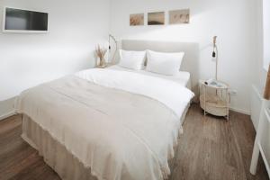 诺德奈Haus Salz & Sand Whg Sand的客房内的白色床、白色床单和枕头
