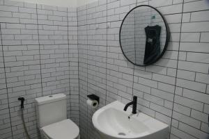 通萨拉The 10 club hostel的一间带卫生间、水槽和镜子的浴室