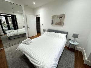 伦敦Modern Majesty 3 Bed 3 Bath House in London的卧室配有白色的床和镜子