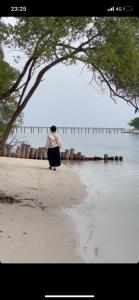VeymandooRihiveli Inn的站在水边的海滩上的女人