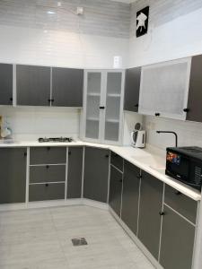 塔伊夫فلل الكناري الراقية的厨房配有灰色和白色的橱柜和微波炉
