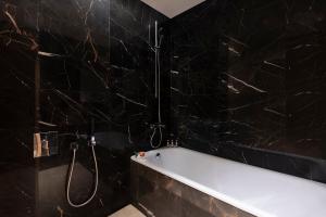 多哈The Bentley Luxury Hotel & Suites的黑色浴室设有浴缸和淋浴。