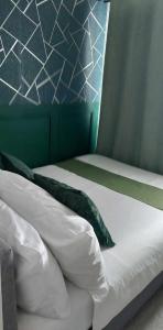 马尼拉Awesome Value, Great Location的一张带白色床单和绿色枕头的床