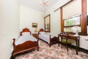 悉尼东悉尼酒店的一间卧室设有两张床、一张桌子和一个窗口。