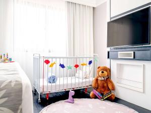 圣保罗美居圣保罗伊比拉普埃拉特权酒店的一只泰迪熊坐在卧室的婴儿床上