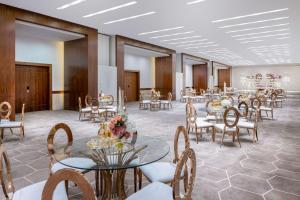 吉达Al Andalus Mall Hotel的宴会厅配有桌椅和鲜花