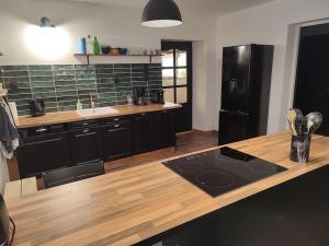 FraizeLogement Spacieux的厨房配有木制柜台和黑冰箱。