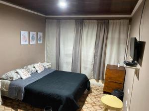 伊瓜苏港Guembe al Rio Hostel的一间卧室配有一张床和一台平面电视