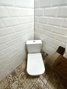 格克切达镇GÖKÇEADA BADEMİ BUTİK OTEL的浴室铺有白色瓷砖,设有白色卫生间。