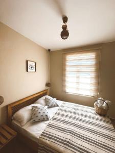 格克切达镇GÖKÇEADA BADEMİ BUTİK OTEL的一间卧室配有一张带条纹毯子的大床