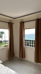 亚喀巴PALM BEACH HOTEL free ticket for pedal boat تذكرة مجانية للالعاب البحرية的一间卧室设有2扇窗户,享有海景