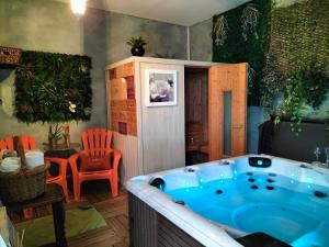 圣布里厄Le Jardin Secret & Spa的配有橙色椅子的客房内的按摩浴缸