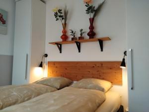 韦斯特卡佩勒SCHELP Bed by the Sea的两张床位于带两瓶花的墙上