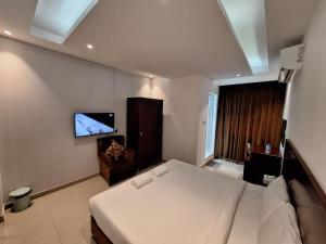 锡卜ALJAWHARA INN HOTEL的卧室配有一张床,墙上配有电视。