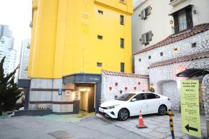 首尔Hotel Golden Hill的停在黄色建筑前面的白色汽车