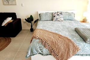麦凯WhitsunStays - Le Beach Shack的一间卧室配有一张带毯子和沙发的床