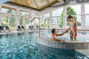 莫尔韦诺丽城阿尔卑斯山健康与美容度假酒店的游泳池里摇着男人手的女人