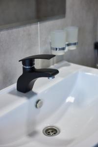 卡拉科尔Karakol Resort的浴室水槽配有黑色水龙头和2个玻璃杯