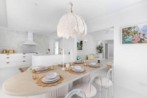 麦凯WhitsunStays - The Cyclades的一间白色的用餐室,配有一张桌子和吊灯