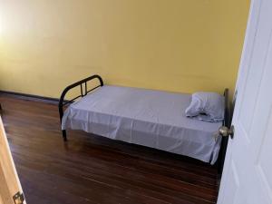 阿拉胡埃拉El Parque Bed and Breakfast的铺有木地板的客房内的一张小床