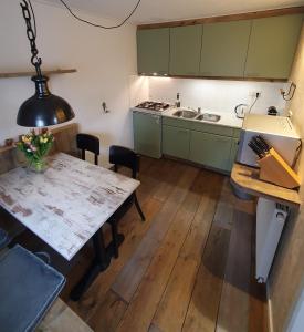 卑尔根Holiday home De Waterput in Bergen NH的厨房配有绿色橱柜和木桌