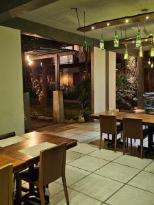 达瓦拉维Royal Tusker Hotel的餐厅设有木桌和椅子及灯