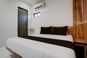 孟买OYO Hotel Vrindavan Residency的一间卧室配有两张床,提供白色的床单和黑色的枕头
