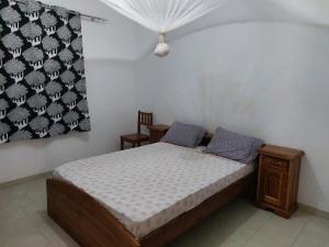 Boukot OuolofLa maison Yaka的一间带床和窗帘的小卧室