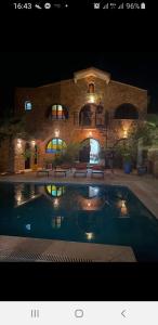 ElmaDar Farah的一座游泳池,在晚上在建筑物前