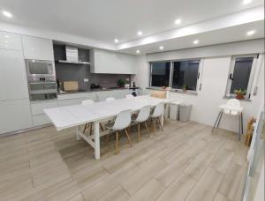 佩尼契SUPERTUBOS HOUSE Peniche的厨房配有白色的大桌子和椅子