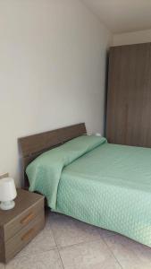 新福卡Appartamento Eurogarden的一间卧室设有一张绿色的床和一个木制床头板