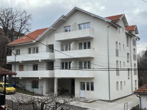 索科矿泉村Milutinn-Jabuka的前面是白色的公寓楼,有黄色的汽车