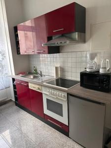 马格德堡Stilvolles Zuhause的厨房配有红色橱柜、炉灶和水槽。