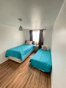 蒙特港Casa en Puerto Montt的铺有木地板的小客房内的两张床