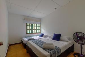 圣玛尔塔CASA DE CAMPO CASTILLETE dentro del PARQUE TAYRONA的一间卧室配有两张床和风扇