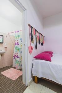 巴卡拉尔Zayali Bacalar - Guest House的一间卧室配有带粉红色枕头的床和一间浴室