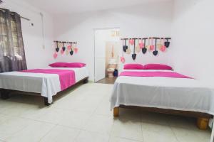 巴卡拉尔Zayali Bacalar - Guest House的白色客房内的两张床和粉红色床单