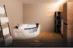 帕苏德尔托纳莱Anemone Bianco Suite Rooms的一间位于客房角落的白色浴缸客房