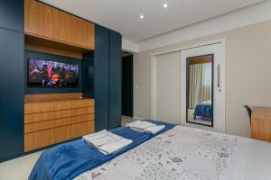 弗洛里亚诺波利斯Confortável Studio com 46,72m²的一间卧室配有电视和一张蓝色墙壁的床