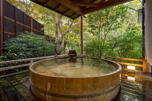 秦野市Jinya Ryokan的树木繁茂的甲板上的大型木制浴缸