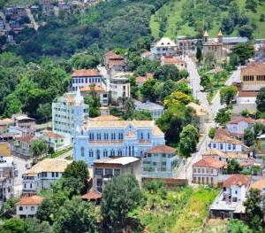 PitanguiPousada Economic Pitangui的山丘上一座蓝色建筑的城镇