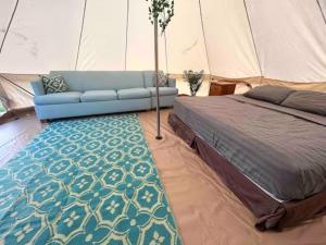 拉耶North Shore Glamping / Camping Laie, Oahu, Hawaii的一间卧室配有一张床,一张沙发位于帐篷内