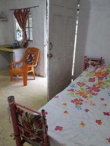 Loma del NaranjoCABAÑA MISSRAÍ TROPICAL的一间卧室配有一张床、一张桌子和一把椅子