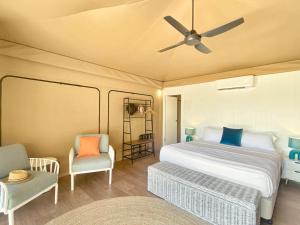 耐莉湾Magnetic Glamping Tent 3的一间卧室配有一张床、两把椅子和一个吊扇
