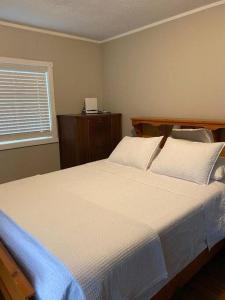 萨尼亚Bluewater Delight的一间卧室配有一张带白色床单的床和一扇窗户。