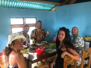 KomodoDua Putri Komodo Homestay的一群人坐在桌子旁吃着食物