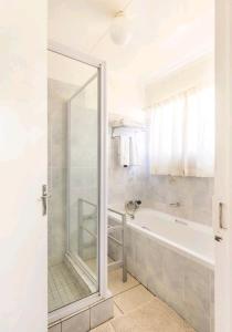 约翰内斯堡Lovely Linden Cottage with Solar Inverter的带淋浴和浴缸及镜子的浴室