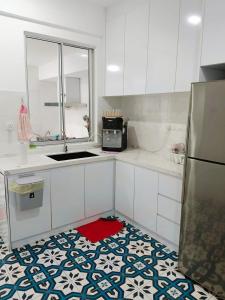 万挠Embun Bayu Musliim homestay的厨房配有白色橱柜和红色地毯。